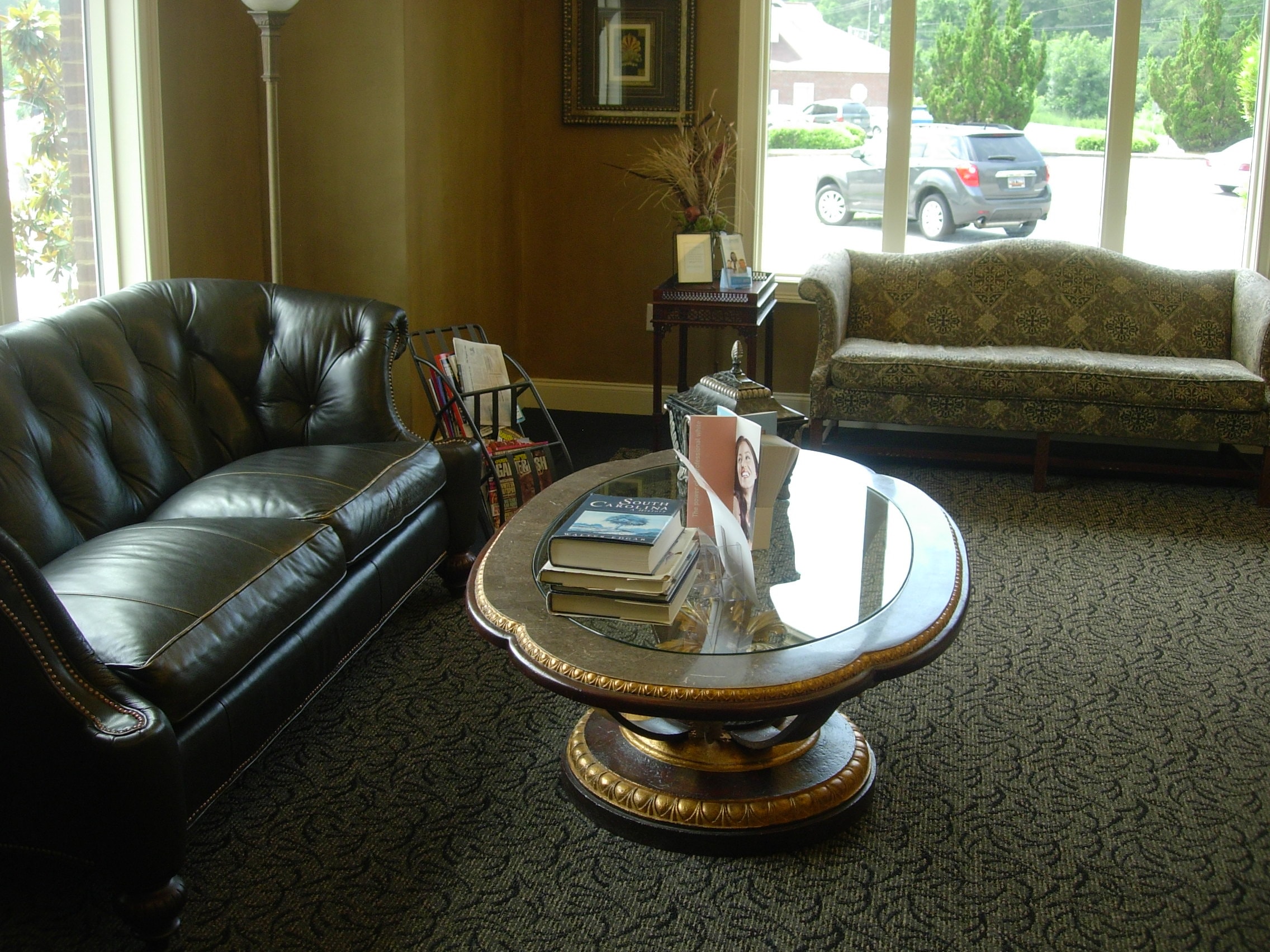 Comfortable waiting room with leather sofa and glass coffee table at Thomas H. Pitts DMD