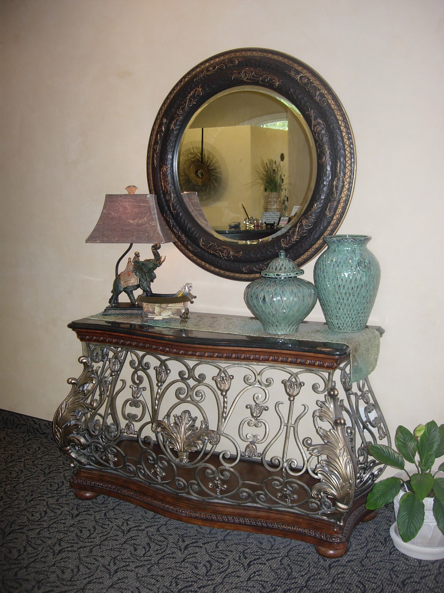 Ornate decorative console table with round mirror and accent pieces at Thomas H. Pitts DMD